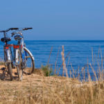 twee-fietsen-op-het-strand-op-de-achtergrond-een-blauwe-zee-op-een-zonnige-dag_83055-282